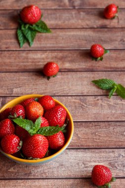 Ahşap arka plan, seçici odak üzerinde bir kapta sulu taze çilek