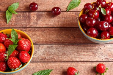 Sulu taze çilek ve ahşap zemin, seçici odak üzerine bir kase kiraz