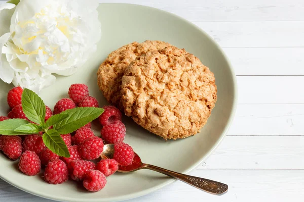 Вкусное печенье с малиной, мятой и белым цветком пиона на тарелке . — стоковое фото