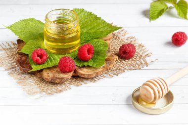 Tatlım, çilek ve ahududu yaprağı bir ahşap stand bir kase. Kaşık bal ile