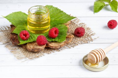 Tatlım, çilek ve ahududu yaprağı bir ahşap stand bir kase. Kaşık bal ile