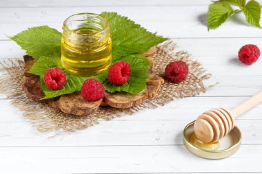 Tatlım, çilek ve ahududu yaprağı bir ahşap stand bir kase. Kaşık bal ile