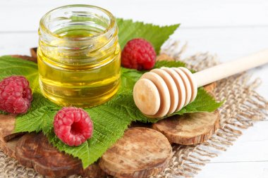 Tatlım, çilek ve ahududu yaprağı bir ahşap stand bir kase. Kaşık bal ile