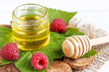 Tatlım, çilek ve ahududu yaprağı bir ahşap stand bir kase. Kaşık bal ile