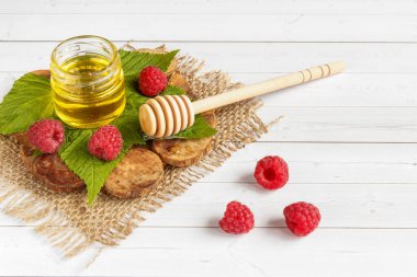 Tatlım, çilek ve ahududu yaprağı bir ahşap stand bir kase. Kaşık bal ile