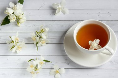 Ahşap arka planda yasemin çiçekli bir fincan çay.