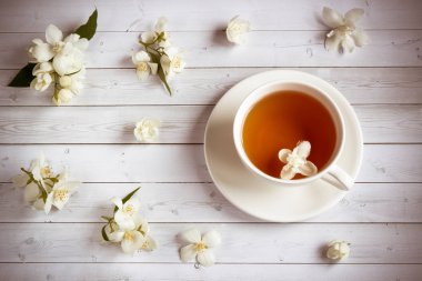 Ahşap arka planda yasemin çiçekli bir fincan çay.