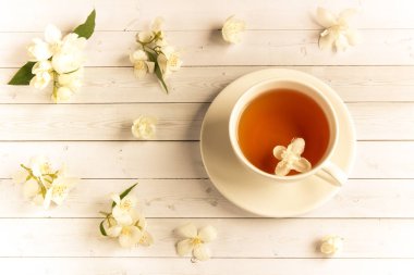 Ahşap arka planda yasemin çiçekli bir fincan çay.