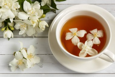 Ahşap arka planda yasemin çiçekli bir fincan çay.