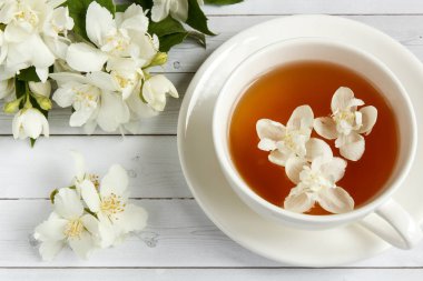Ahşap arka planda yasemin çiçekli bir fincan çay.
