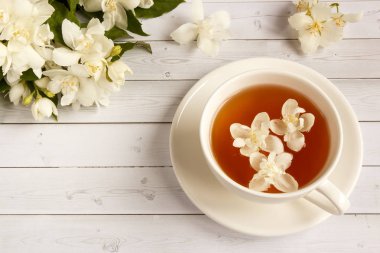 Ahşap arka planda yasemin çiçekli bir fincan çay.