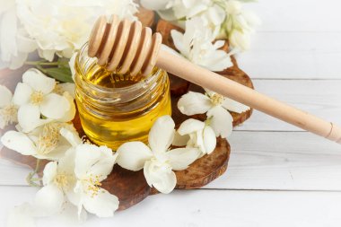 Kavanoz ve bir kaşık bal Yasemin çiçekleri ile ahşap bir stand ile