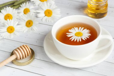 Bir bardak papatya çayı ve bal Beyaz ahşap zemin üzerinde