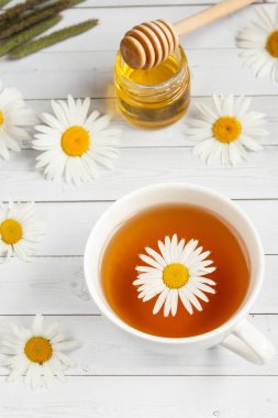 Bir bardak papatya çayı ve bal Beyaz ahşap zemin üzerinde