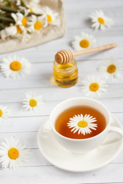 Bir bardak papatya çayı ve bal Beyaz ahşap zemin üzerinde