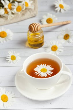 Bir bardak papatya çayı ve bal Beyaz ahşap zemin üzerinde