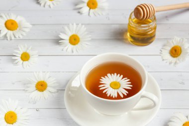 Bir bardak papatya çayı ve bal Beyaz ahşap zemin üzerinde