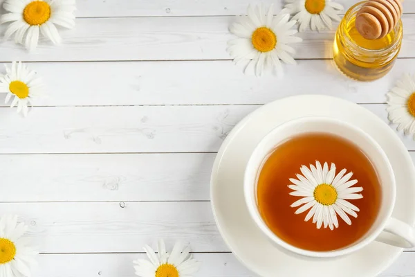 Ένα φλιτζάνι τσάι χαμομήλι και μέλι σε άσπρο φόντο ξύλινη — Φωτογραφία Αρχείου