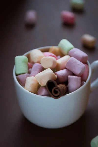 Chocolate quente em uma xícara branca com marshmallows coloridos em um fundo escuro. Foco seletivo . — Fotografia de Stock