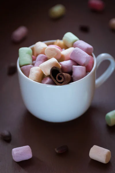 Chocolate quente em uma xícara branca com marshmallows coloridos em um fundo escuro. Foco seletivo . — Fotografia de Stock