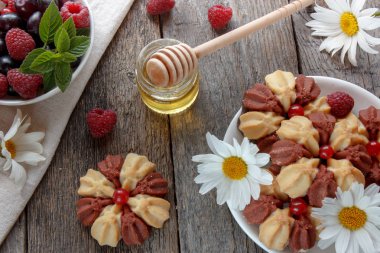 Taze çilek beyaz tabakta ve ahşap arka plan bahçe çiçekleri ile bisküvi. Seçici odak.