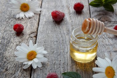 Ahşap arka plan üzerinde banka ile bal ahududu ve çiçek chamomiles. Seçici odak kopya alanı