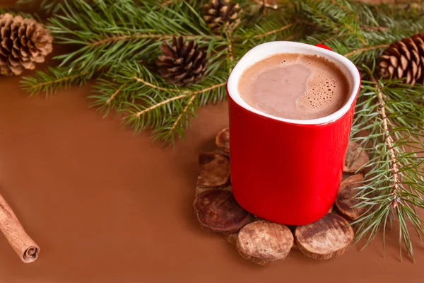 Vánoční tradiční horký nápoj kakao v červené pohár, jedle větve a šišky na místa kopie tmavé dřevěné pozadí — Stock fotografie