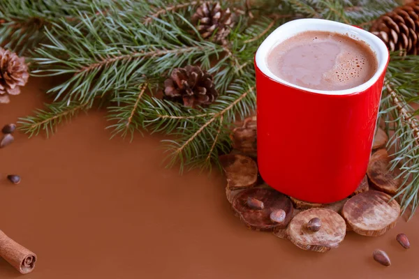 Vánoční tradiční horký nápoj kakao v červené pohár, jedle větve a šišky na místa kopie tmavé dřevěné pozadí — Stock fotografie
