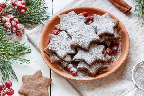 Традиционное рождественское пряничное печенье, звезды в сахарной пудре на тарелке. Ягоды красной рованской ели . — стоковое фото