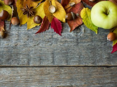 Sonbahar arka plan ile kuru yaprakları, fındık, meşe palamutları tarçın baharat ahşap masa üzerinde. Kopya alanı