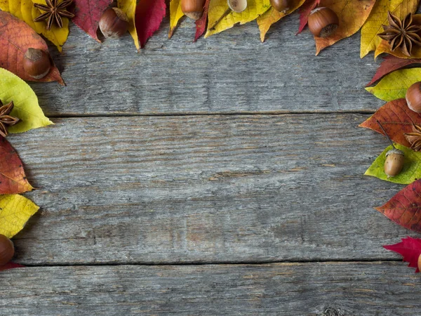 Fondo autunnale con foglie secche, noci, spezie alla cannella ghiande su tavolo di legno. Copia spazio — Foto Stock