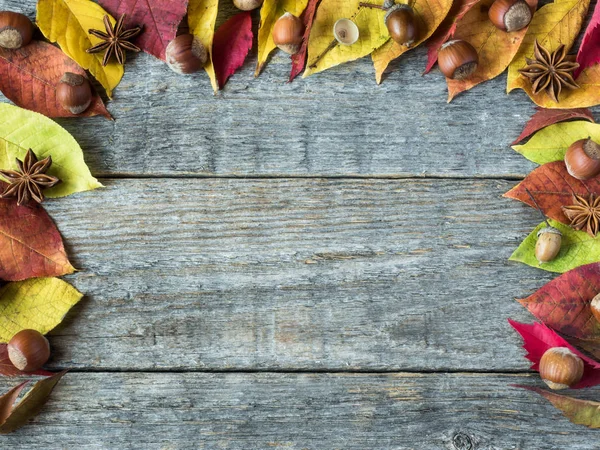 Autumn background with dry leaves, nuts, acorns cinnamon spices on wooden table. Copy space — Stock Photo, Image