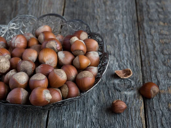 Lískové ořechy v prolamované deska na teriann pozadí rustikální — Stock fotografie