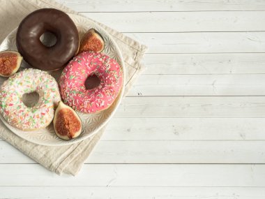 Plaka kahve çekirdekleri ahşap rustik arka plan üzerinde renkli donut yanıyor