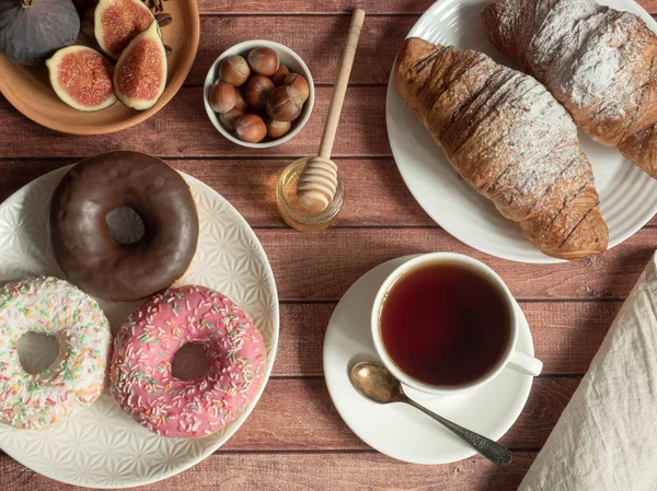 Desayuno donut croissant higos nueces en los platos y té Copa en la mesa — Foto de Stock