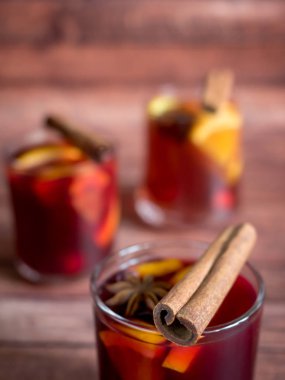 Cam kadeh kırmızı şarap mulled şarap tarçın baharat ve turuncu ahşap bir zemin üzerine. Seçici odak