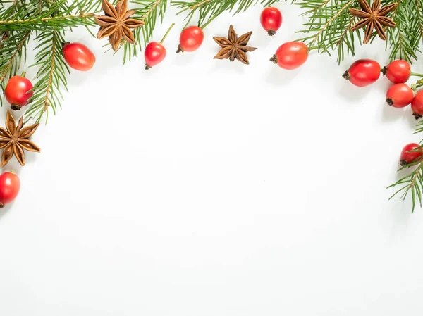 Рождественские украшения на белом фоне, ягоды шиповника, звезды, еловые ветви. копировальное пространство — стоковое фото