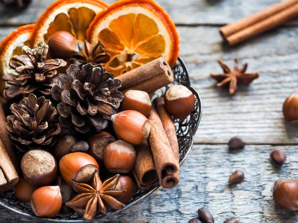 Ingredientes de invierno nueces, conos, naranjas, anís estrella de canela en un tazón. Estilo rústico —  Fotos de Stock