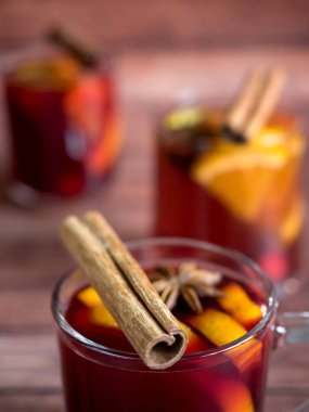 Cam kadeh kırmızı şarap mulled şarap tarçın baharat ve turuncu ahşap bir zemin üzerine. Seçici odak