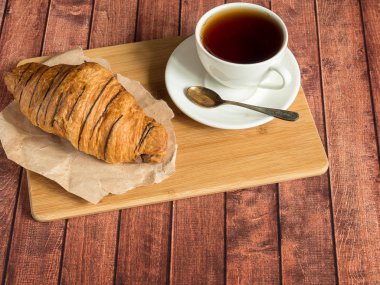 Kahvaltı kruvasan ve çay Tekstil peçeteye. Koyu ahşap arka plan.