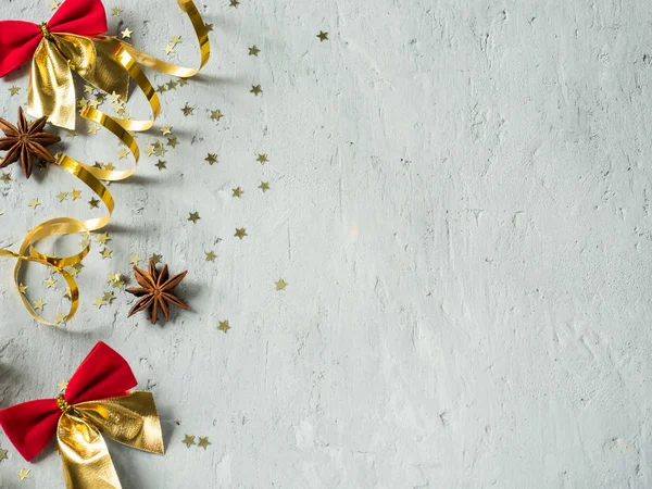 Рождественский декоративный красный лук и золотая лента на сером бетонном фоне подражания — стоковое фото