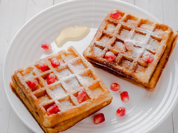 Köstliche Wiener Waffeln mit Honig und Granatapfelkernen auf weißem Teller, heller Holzgrund — Stockfoto