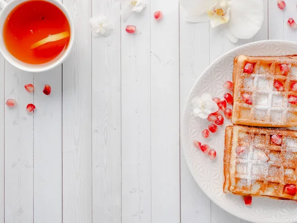 Köstliche köstliche Wiener Waffeln mit Honig und Granatapfelkernen auf einem weißen Teller, heller Holzhintergrund Kopierraum — Stockfoto