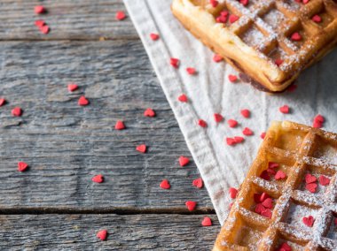 Pudra şekeri ve rustik ahşap arka plan kopya alanı üzerinde kırmızı kalpler ile yumuşak Viyana Belçika waffle