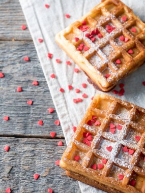 Pudra şekeri ve rustik ahşap arka plan üzerinde kırmızı kalpler ile yumuşak Viyana Belçika waffle