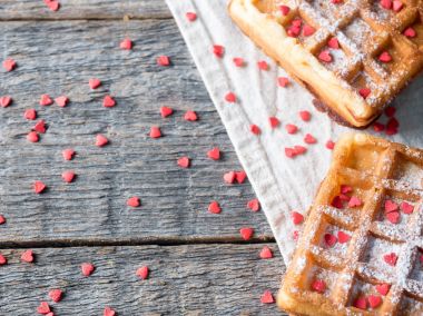 Pudra şekeri ve rustik ahşap arka plan kopya alanı üzerinde kırmızı kalpler ile yumuşak Viyana Belçika waffle