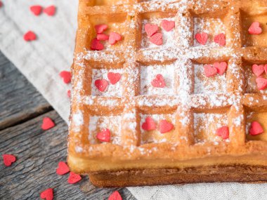 Pudra şekeri ve rustik ahşap arka plan üzerinde kırmızı kalpler ile yumuşak Viyana Belçika waffle