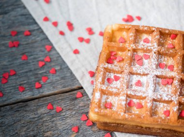 Pudra şekeri ve rustik ahşap arka plan kopya alanı üzerinde kırmızı kalpler ile yumuşak Viyana Belçika waffle