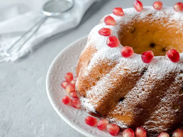 Pastel de Navidad en forma de corona con azúcar en polvo y semillas de granada en un plato blanco Enfoque selectivo —  Fotos de Stock