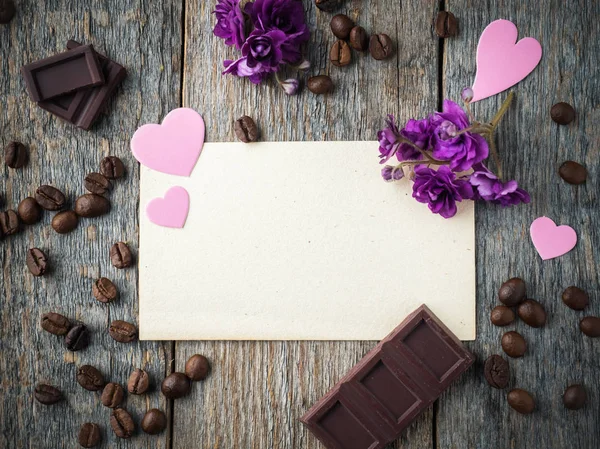 Decorações para dia dos namorados corações de papel, violetas, café e chocolate no papel velho e fundo de madeira — Fotografia de Stock